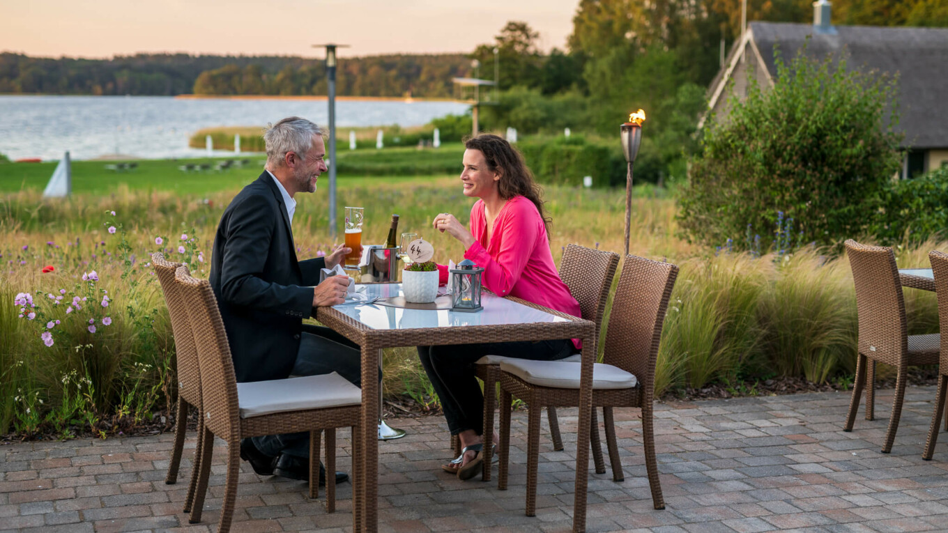 Ein Paar beim Abendessen auf einer Terrasse mit Seeblick